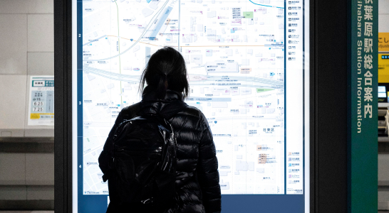 A woman looking at a map on a big screen, maybe planning a journey or looking for directions.