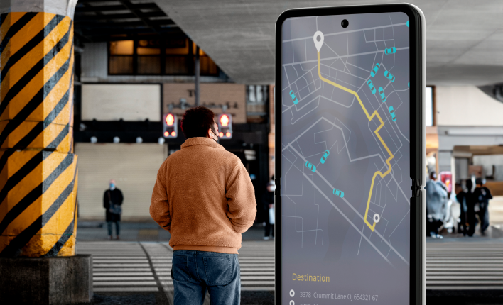 A man is in front of a smartphone that has kiosk navigation wayfinding software through maping.